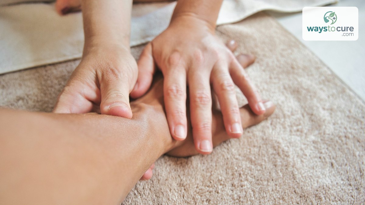 Two hands applying pressure to another person's hand resting on a soft beige towel