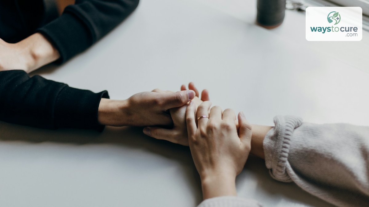 Two people holding hands across a white table in support